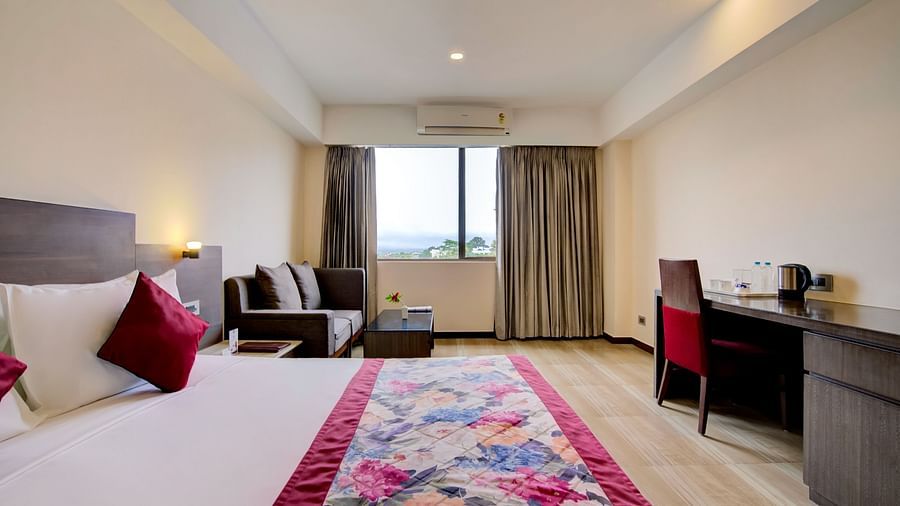 Well-lit room with a colourful runner, writing desk, and window view at Voyage Milestone Hotel and Banquet Siliguri
