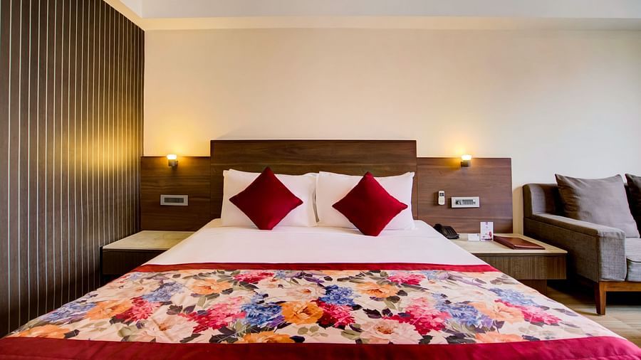 Deluxe room with a floral bedspread, bedside lamps, and neutral-toned décor at Voyage Milestone Hotel and Banquet Siliguri