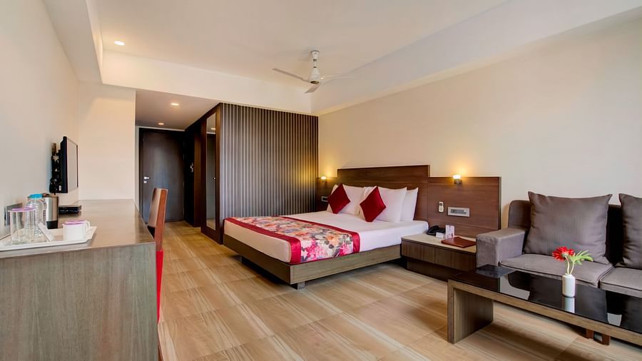 Modern hotel suite with a king size bed, sofa seating area, and wooden flooring at Voyage Milestone Hotel and Banquet Siliguri