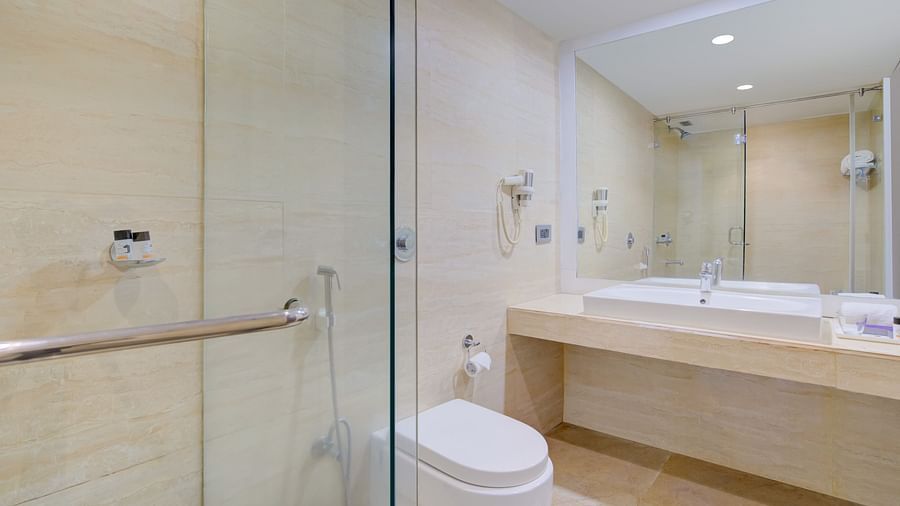 Elegant bathroom with a glass shower enclosure, modern fixtures, and wide vanity at Voyage Milestone Hotel and Banquet Siliguri