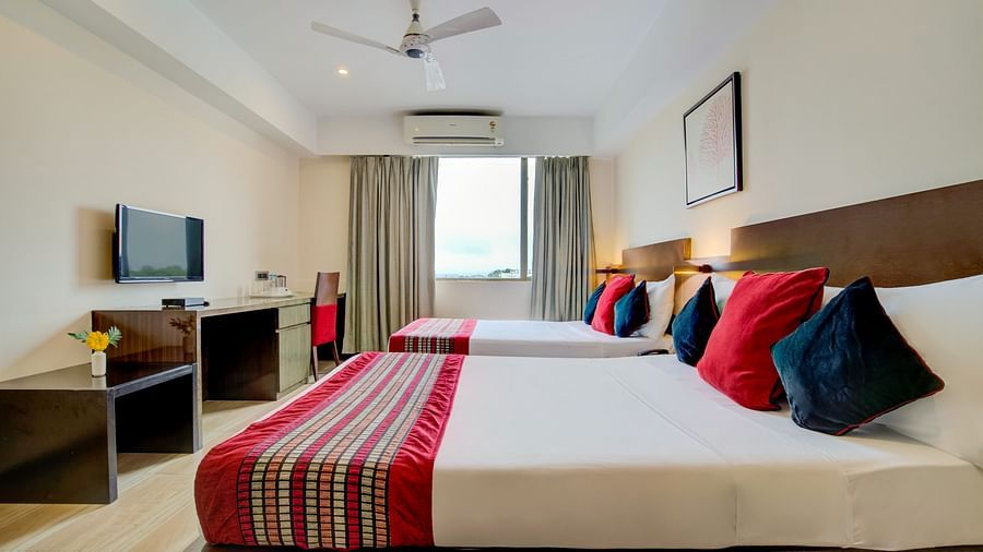 Modern room featuring a large bed with vibrant cushions, TV, and work desk at Voyage Milestone Hotel and Banquet Siliguri
