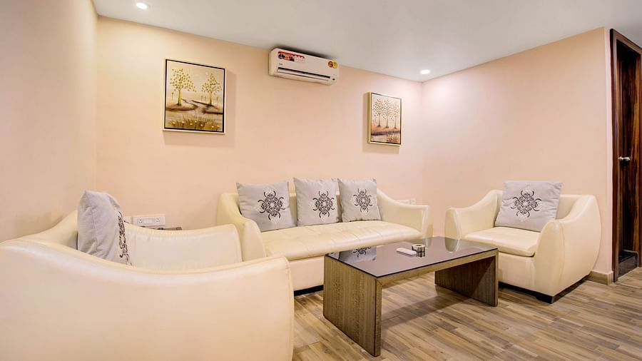 Cosy suite with a cream-toned sofa set, centre table, wall-mounted artwork, and ambient lighting at Voyage Milestone Hotel and Banquet Siliguri