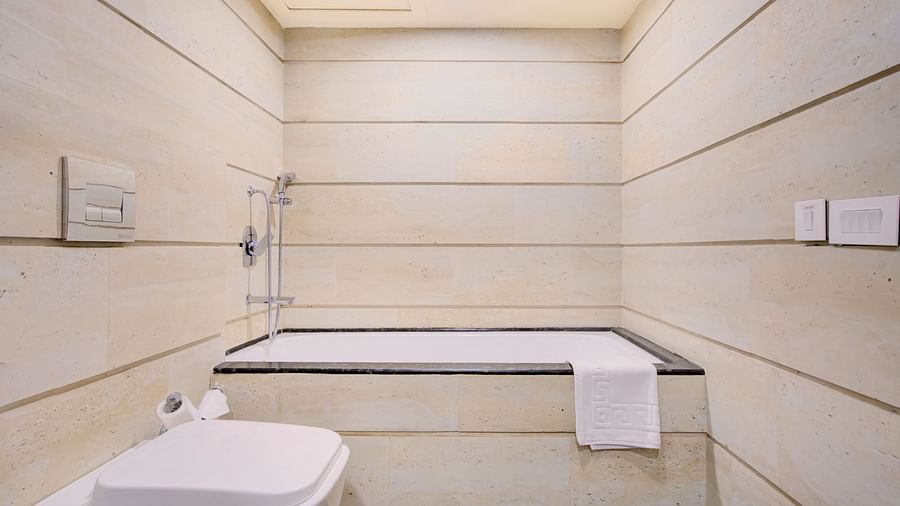Modern bathroom with a walk-in shower, bathtub, and sleek cream-toned walls at Voyage Milestone Hotel and Banquet Siliguri