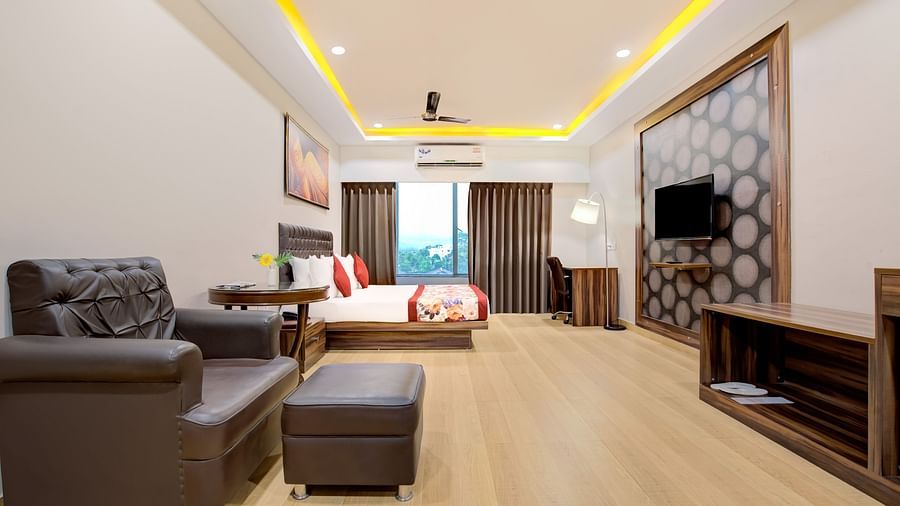 Spacious suite with a double bed, sofa seating, wooden flooring, and ambient ceiling lighting at Voyage Milestone Hotel and Banquet Siliguri