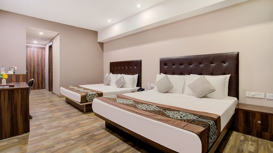 Twin-bed room with plush bedding, reading lamps, and a warm-toned interior at Voyage Milestone Hotel and Banquet Siliguri