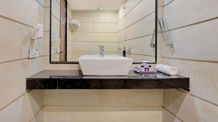 Bathroom vanity area with a wide mirror, modern sink, and elegant tile work at Voyage Milestone Hotel and Banquet Siliguri