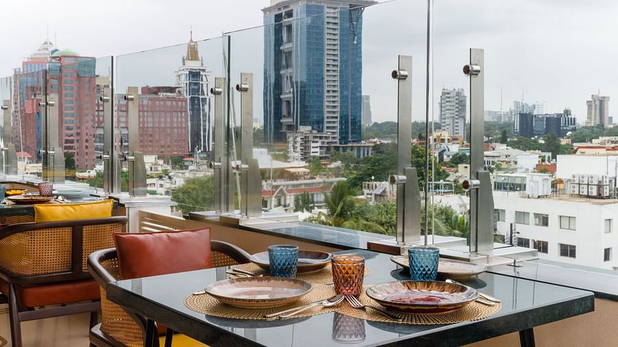 Rooftop restaurant with city skyline views and neatly set dining tables arranged along the railing.