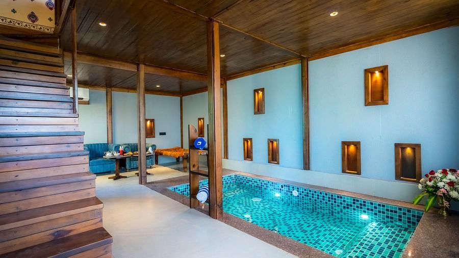A Premium Duplex Tent featuring  a plunge swimming pool, a sofa set, with centre table, and a flight of wooden stairs at The Baagh Ananta Elite, Ranthambore