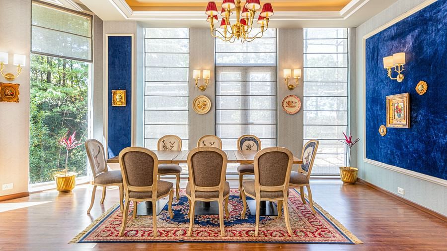 A table with chairs around it under a beautiful chandelier in the club house - The Manor Luxury Hotel, Shimla