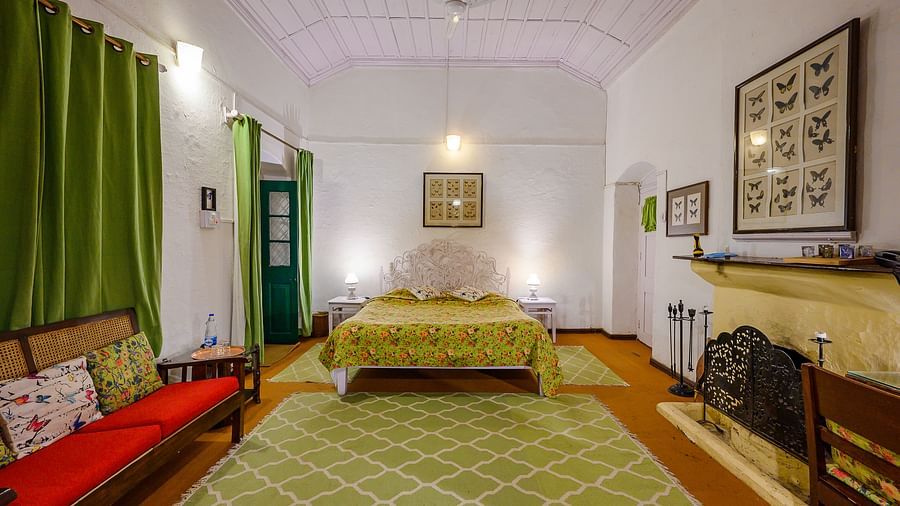 Butterly room with pristine walls, a double bed, a seating area and a fireplace - Ramgarh Bungalows, Nainital.