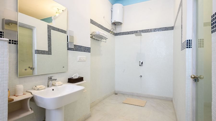 A bathroom with a sink, a mirror mounted to the wall, and a geyser in the background. - Tijara Fort-Palace - 19th Century, Alwar