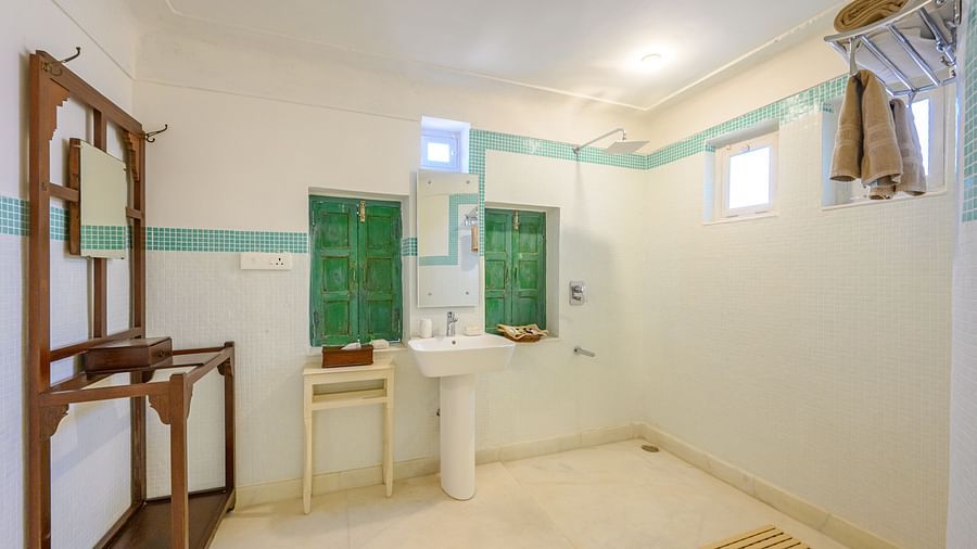 A bathroom with a sink, small windows, a wooden stand, and a hanging towel, in a room with a light colored floor. - Tijara Fort-Palace - 19th Century, Alwar