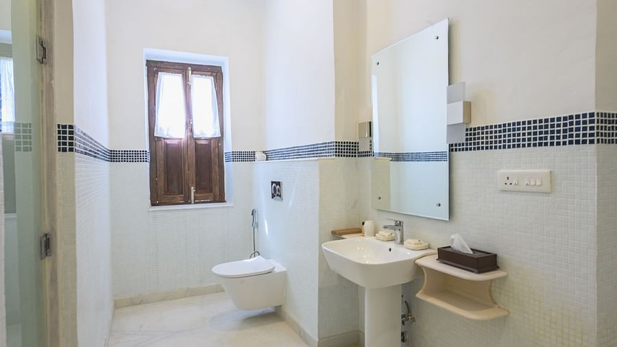 A bathroom with a sink, a mirror mounted to the wall, and a window in the background. - Tijara Fort-Palace - 19th Century, Alwar