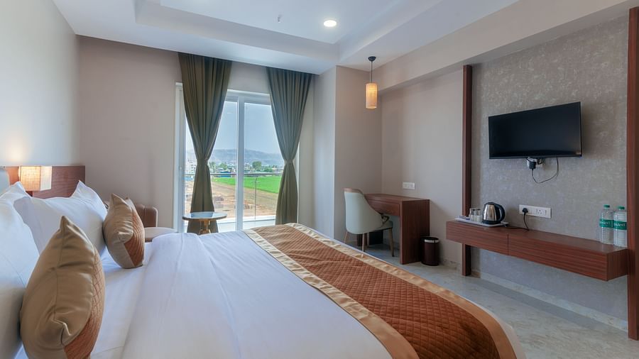 A double bed with a tv opposite it inside Super Deluxe Room - VITS Satyajeet Karad