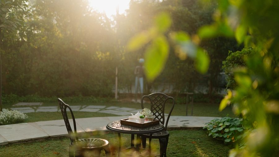 Outdoor seating at Karma Chalets with a round table near a water body and garden area during sunset.