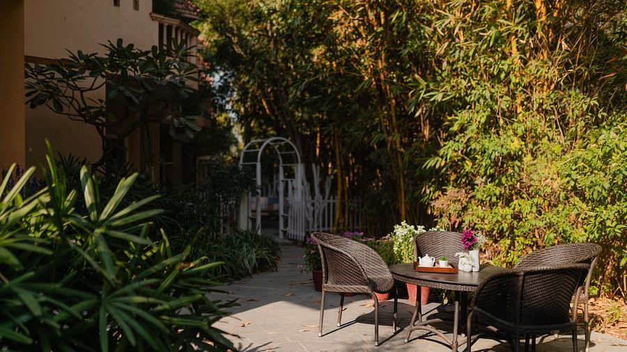 Outdoor seating at Karma Chalets with a black table and two chairs near dense green plants.