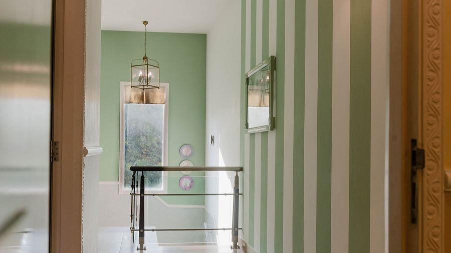 A hallway at Karma Chalets with striped green walls, a hanging light, and doors visible at the end.