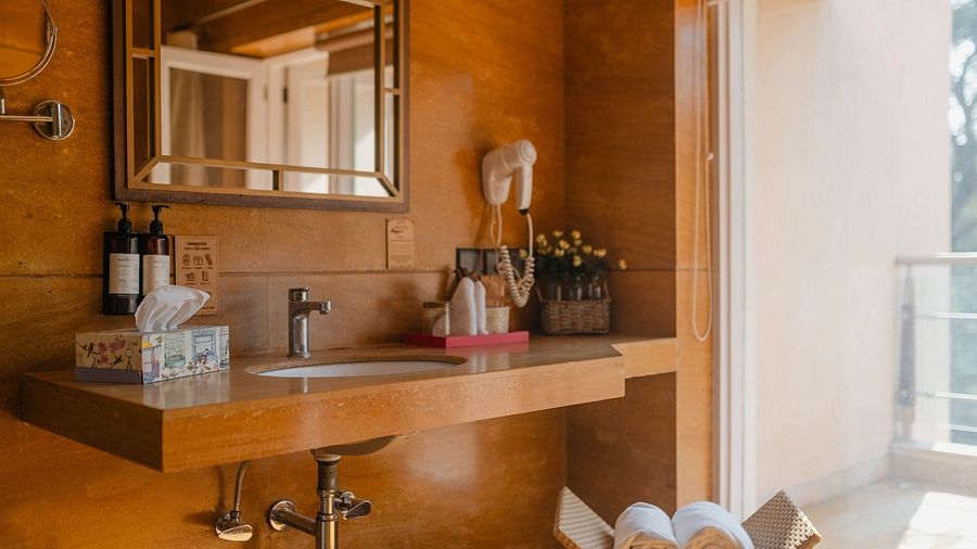 A bathroom at Karma Chalets with a mirror, sink, and toiletry items on a wooden counter.