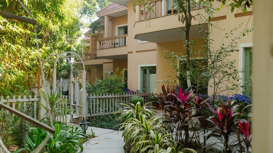 Exterior pathway at Karma Chalets with green plants, trees, and building entrances visible.