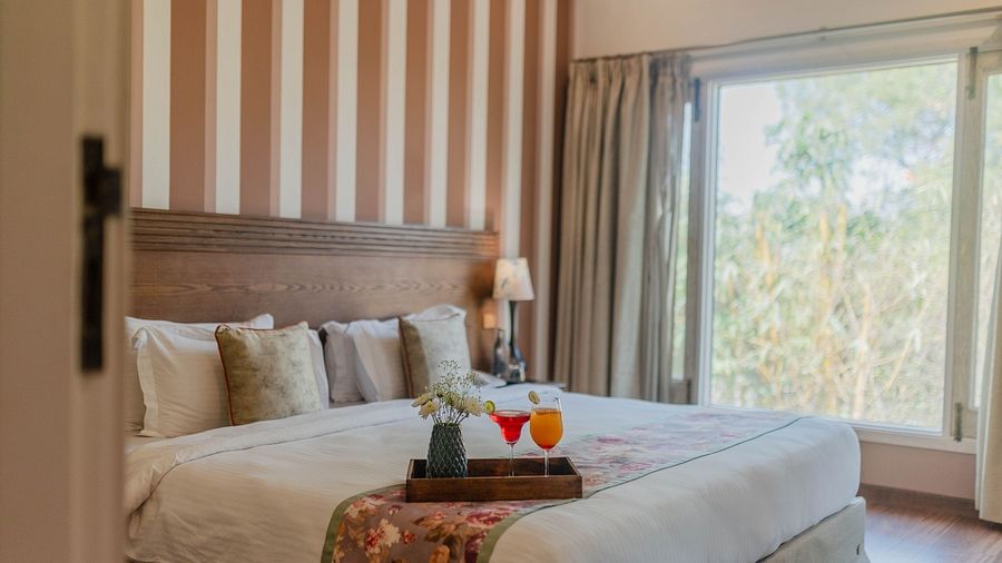 A bedroom at Karma Chalets with a double bed, striped wall panel, and a large window.