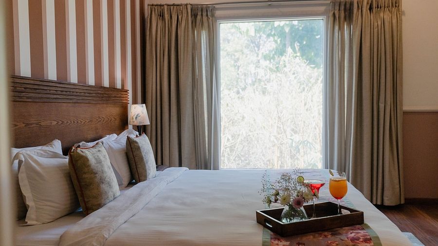 A bedroom at Karma Chalets with a double bed, striped wall panel, and a large window.