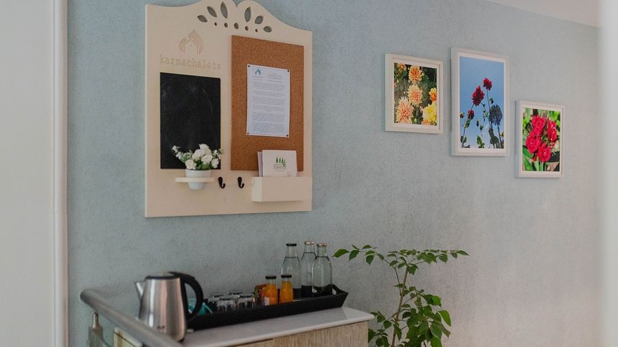 A tea and coffee setup at Karma Chalets with a kettle, mugs, mirror, and wall art on a blue wall.