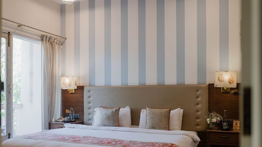 A bedroom at Karma Chalets with a double bed, striped wall panel, and a large window.
