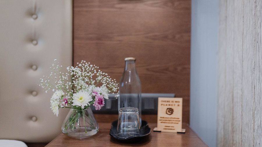 A side table at Karma Chalets with a glass water bottle, vase of flowers, and welcome signage.