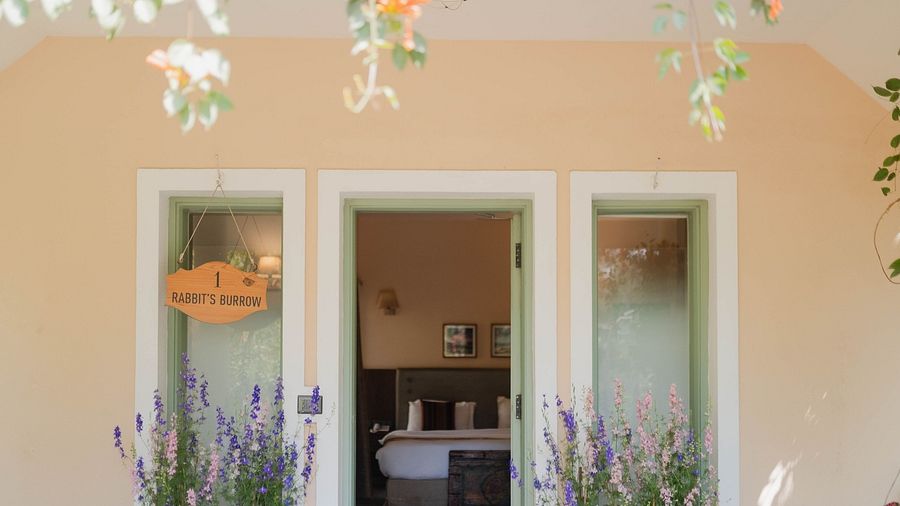 Exterior view of a Karma Chalets unit with two doors, potted plants, and hanging decor.