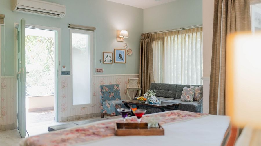 A bedroom at Karma Chalets with a bed, seating area, and an open door showing greenery outside.