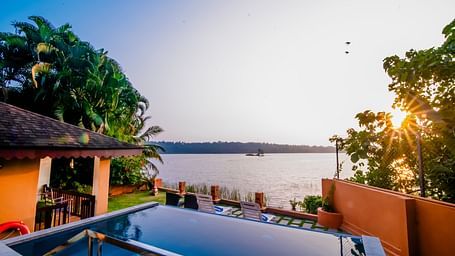 Infinity pool with a stunning sunset view over the water at a resort.