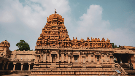Side view of Brihadeeswarar Temple showcasing towering Chola stone architecture and intricate carvings against the sky