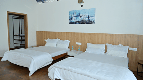 A room at Hilllock Vista Homestay by Aarika Resorts, with two beds, pillows, spreads, and a door leading to an inner space.