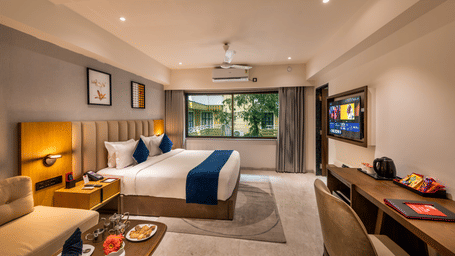 Comfortable stay space with large bed, work desk, and warm lighting at Lords Studio Inn, Jamnagar.