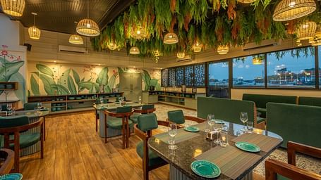 Side shot of interior of The Gaia Gourmet restaurant at Vishranti Hotel, Dehradun, featuring a well-lit dining area with wooden floors.