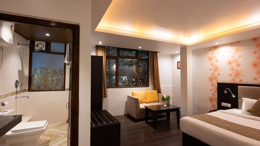 A bedroom featuring a sofa and an open washroom door at Avianna Hungry Jack, Gangtok.