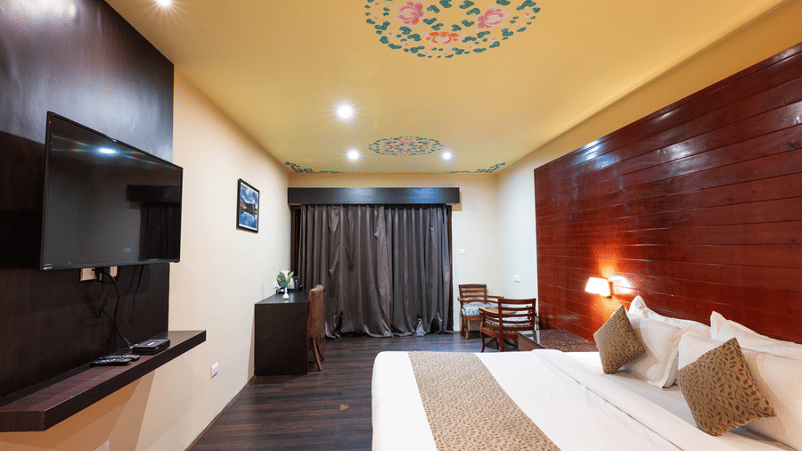 A bed with an artistic painting on the ceiling, adding charm to the room at Avianna Hungry Jack, Gangtok.