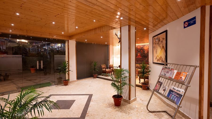 An entrance with warm lighting, wooden ceiling, and a magazine rack near the doorway at Avianna Hungry Jack, Gangtok.