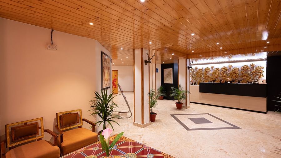 A lobby area with wooden interiors, vibrant decor, and a view of the reception desk at Avianna Hungry Jack, Gangtok.