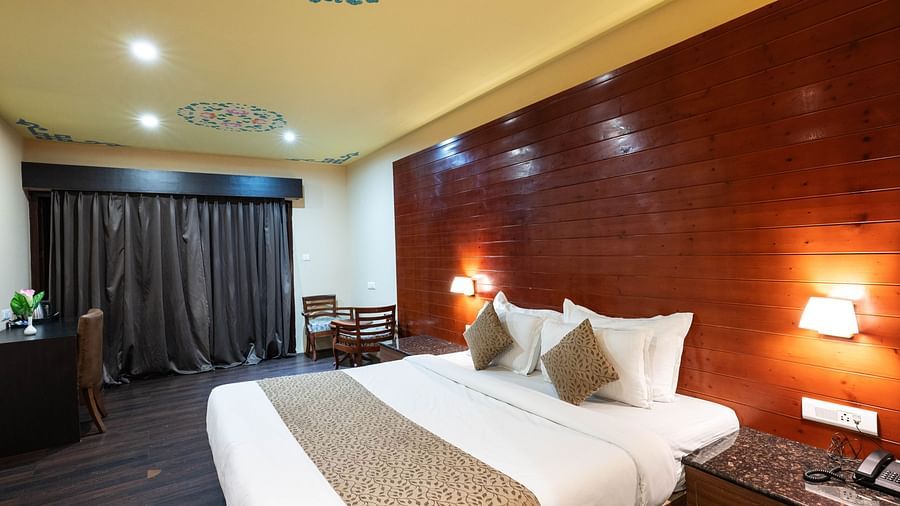 A bedroom with two lights on either side of the bed and a telephone placed on a bedside table next to the bed at Avianna Hungry Jack, Gangtok.