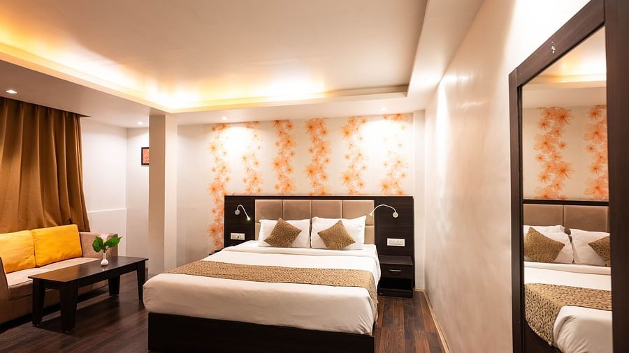 A bedroom with a seating arrangement beside it, and a curtain drawn over the window at Avianna Hungry Jack, Gangtok.
