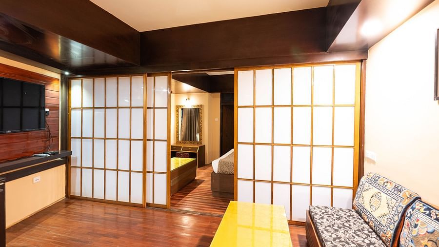 A room with wooden flooring, a cozy seating area, and sliding doors leading to a bedroom at Avianna Hungry Jack, Gangtok.