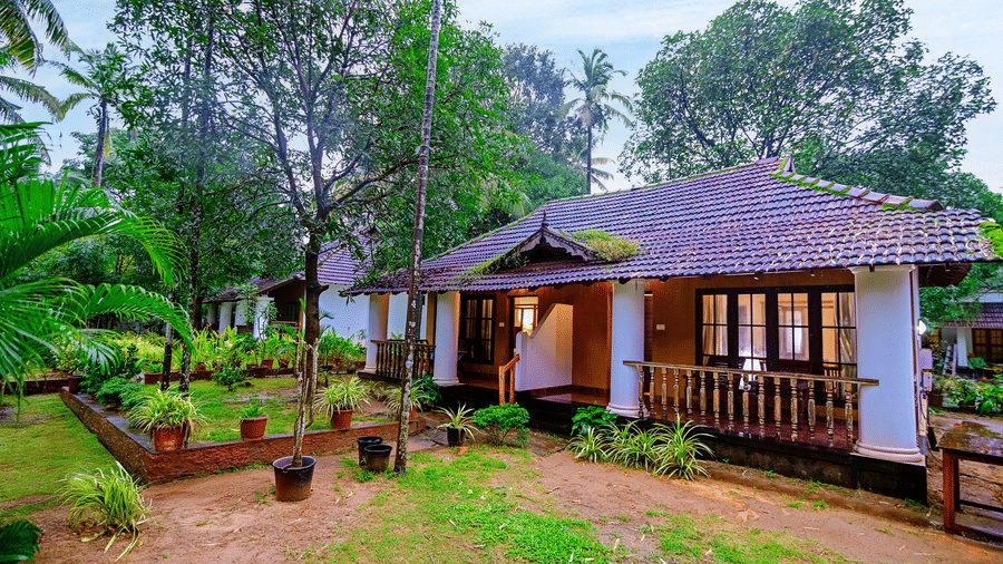 A facade view of a villa with tiled roof, a wraparound balcony and chairs in it at Ayur On The Beach Nattika.