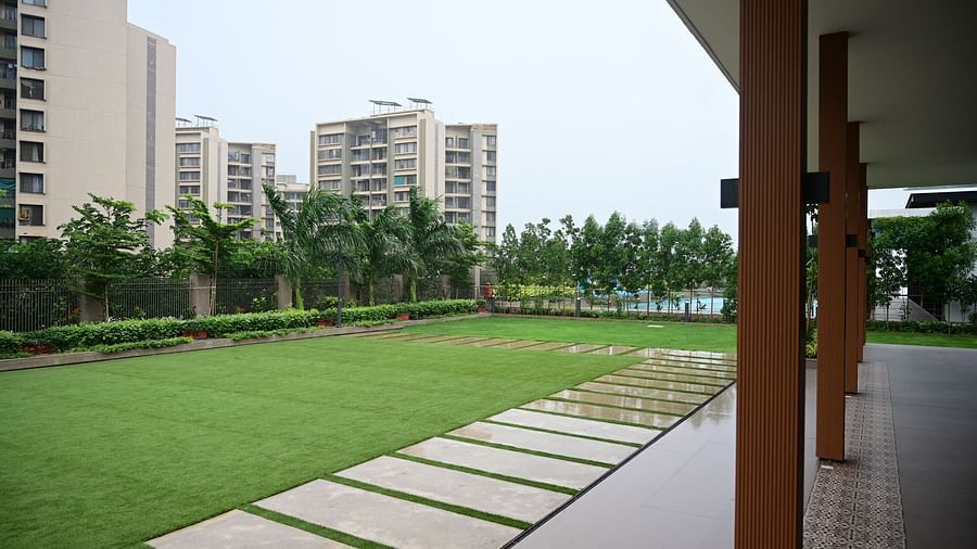 Lawn with pathway leading to a building and cityscape in the background.