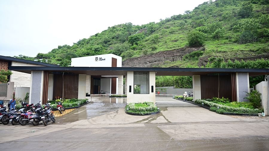 A building with a green hillside backdrop and a parked vehicle.