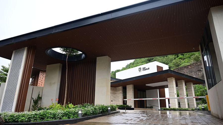 Entrance with a covered drive and gate, leading to a building set against a hillside.