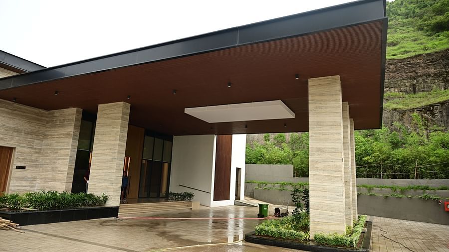 Building entrance with covered porch, columns, and a hillside backdrop.