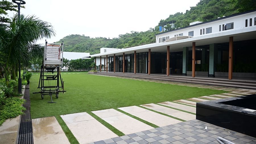 Building with a long porch, lawn, play equipment, and a paved area.