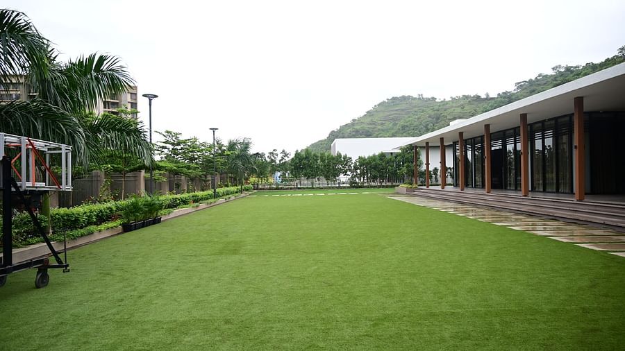 Open lawn with a building on one side and a basketball hoop on the other.