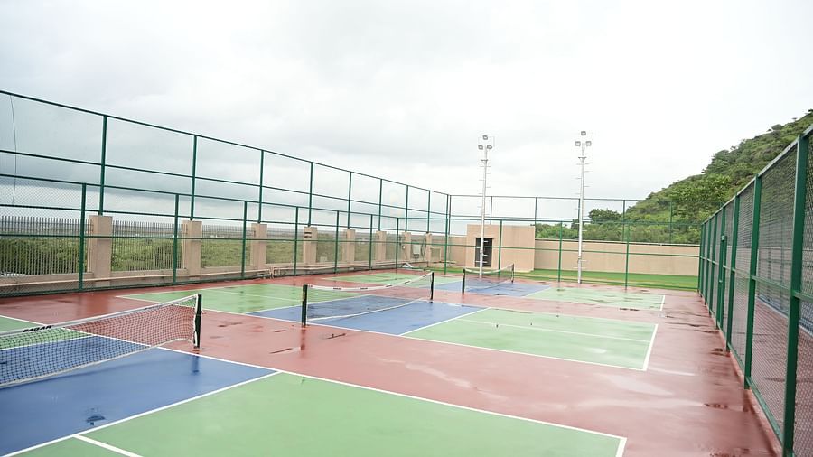 image featuring three tennis courts under a cloudy sky at club charholi, pune